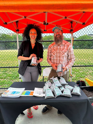 two people selling or giving away bags of compost